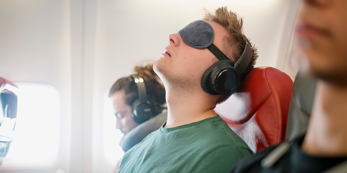 A sleeping passenger on a flight wearing an  eye mask